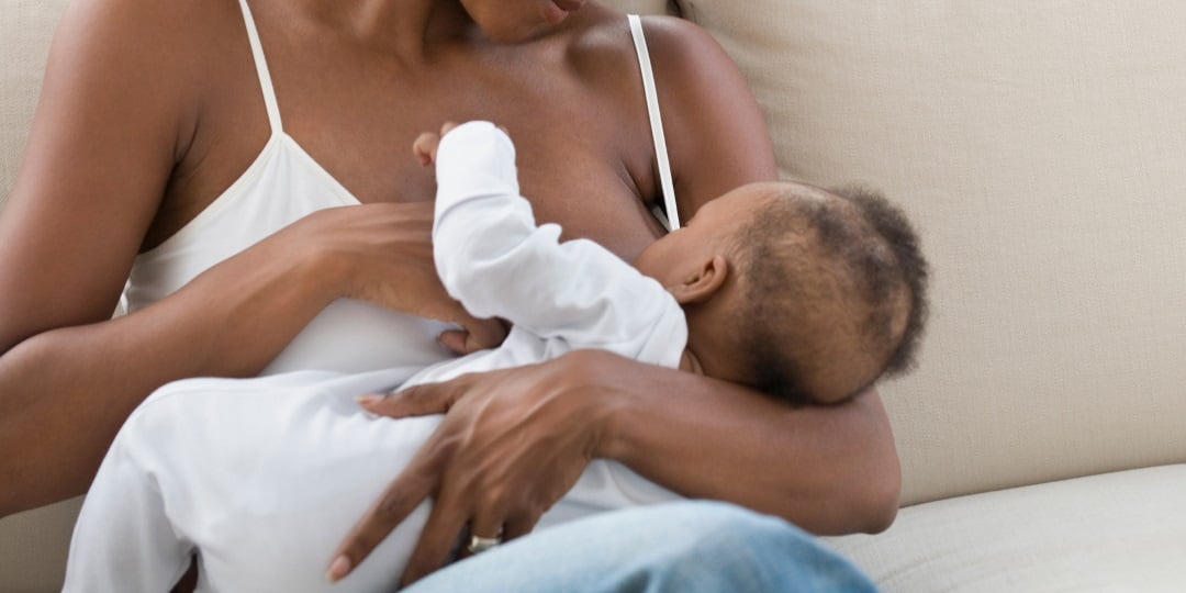 Mulher negra amamentando o seu bebê