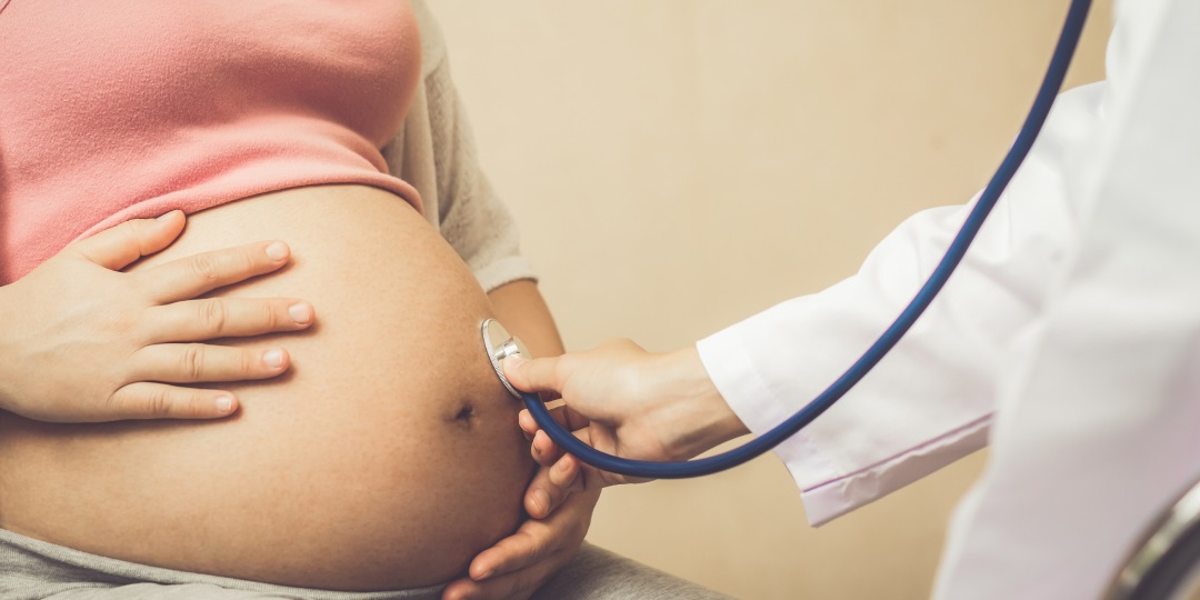 Médico examina com estetoscópio barriga de mulher grávida