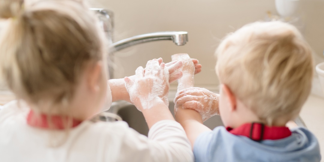 Crianças loiras lavando as mãos com sabão na pia