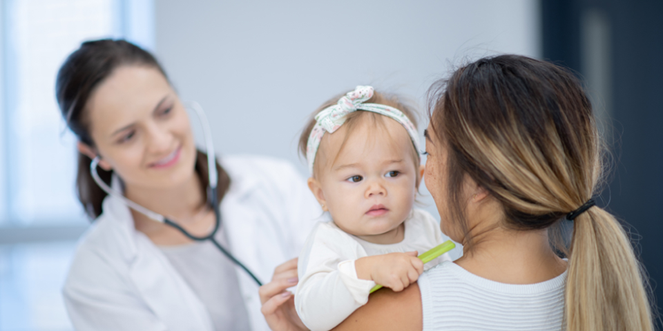 Mulher segurando bebê e conversando com médica