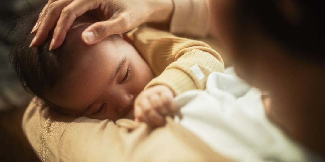 Bebê recém nascido dorme enquanto é acariciado pela mãe