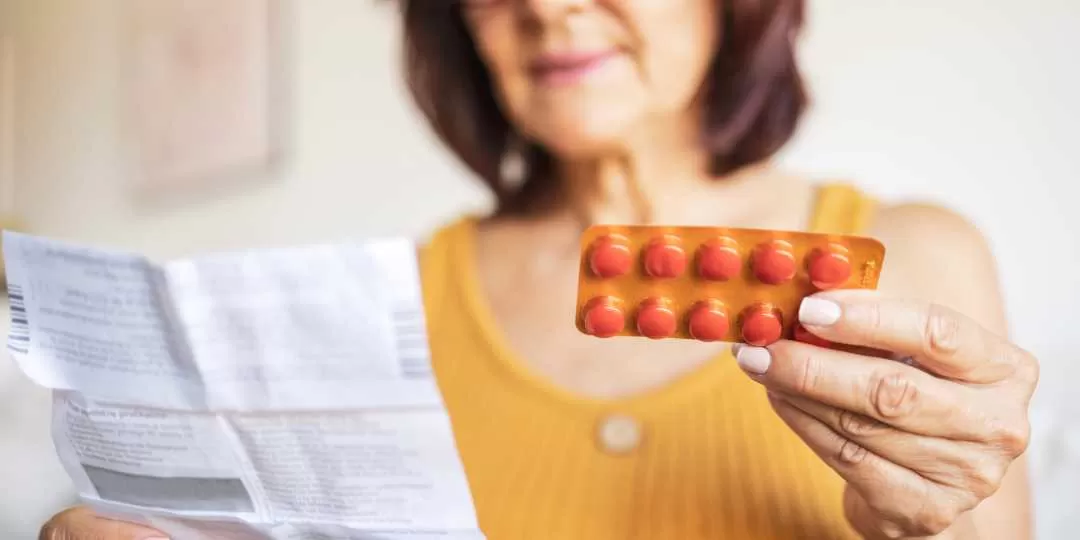 Mulher segurando cartela de medicamentos