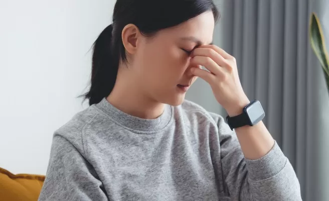 Mulher pressiona região entre os olhos com os dedos