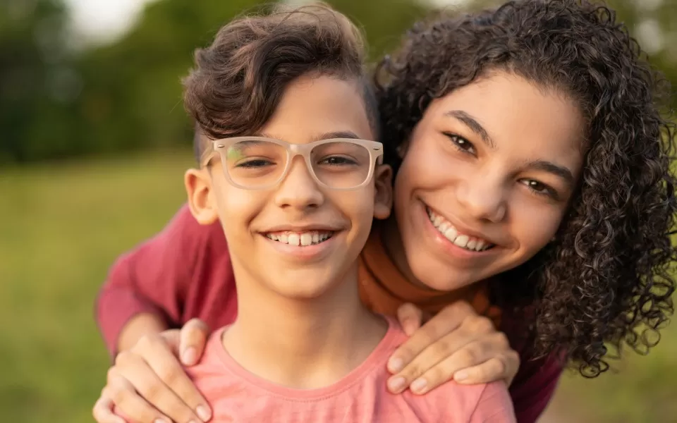 Crianças se abraçam sorrindo ao ar livre