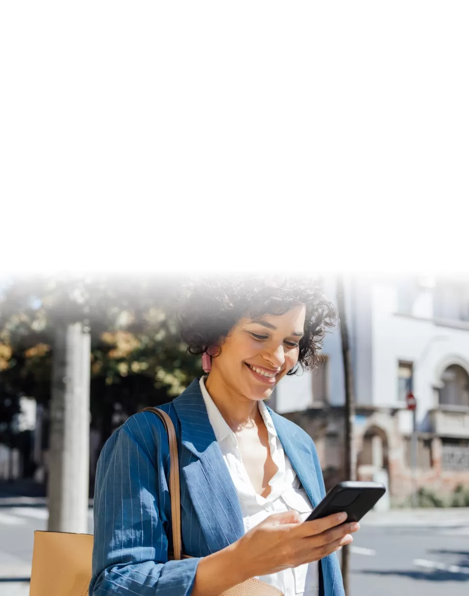 Banner shortmed mulher sorridente olhando para o celular na rua