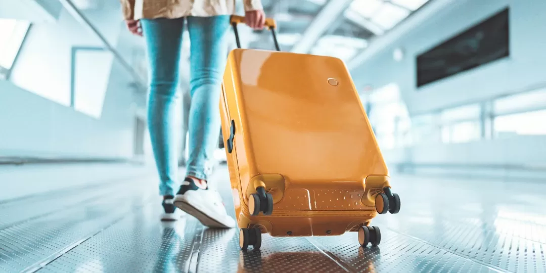 Pessoa com mala de rodinha em corredor de aeroporto