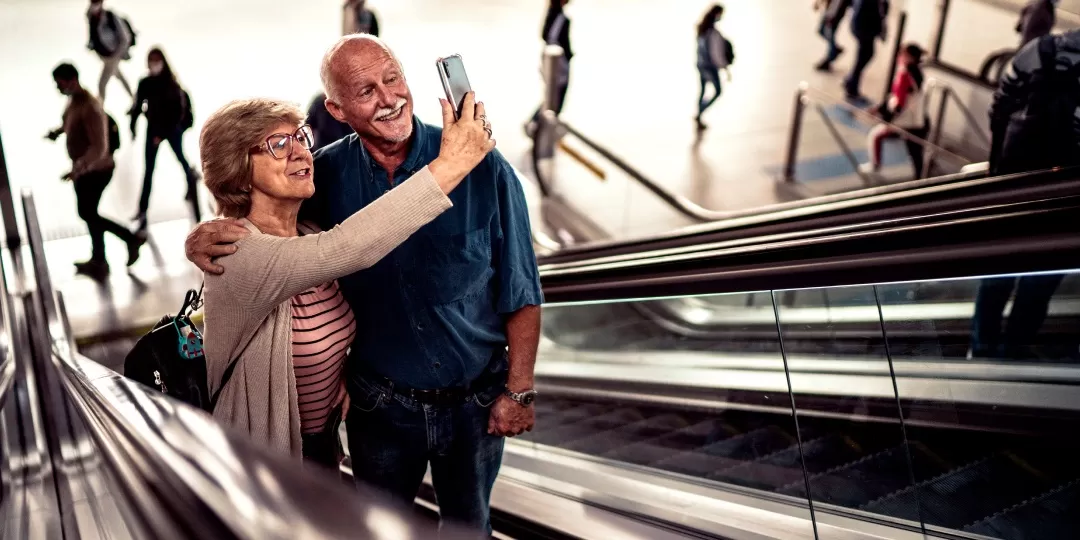 Casal de idosos na escada rolante tirando selfie no celular