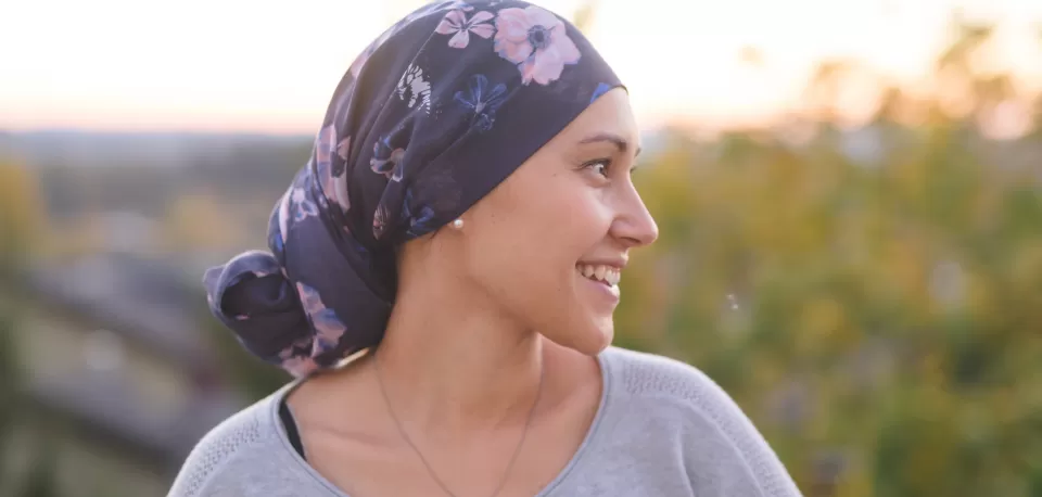 Mulher com faixa na cabeça olha feliz para o horizonte